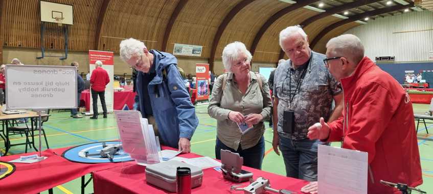 in de hal staan 4 mensen bij de tafel met uitgestalde drones